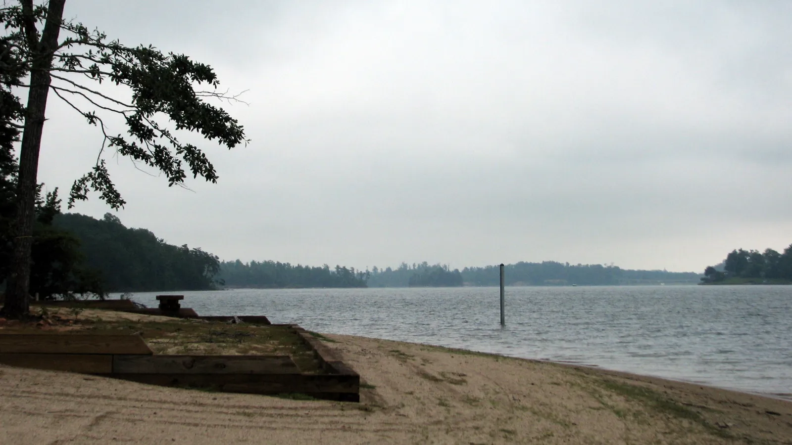 A sandy beach on Lake James at Lake James State Park, under a cloudy sky