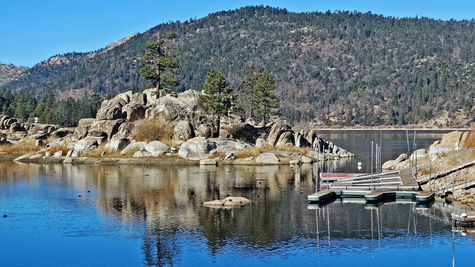 Rocky islets and a small dock in Boulder Bay, with forested hills behind