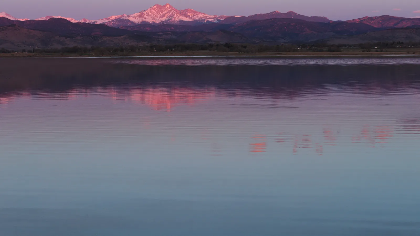 Mount Meeker glowing pink at sunrise, reflected in the still water of McIntosh Lake
