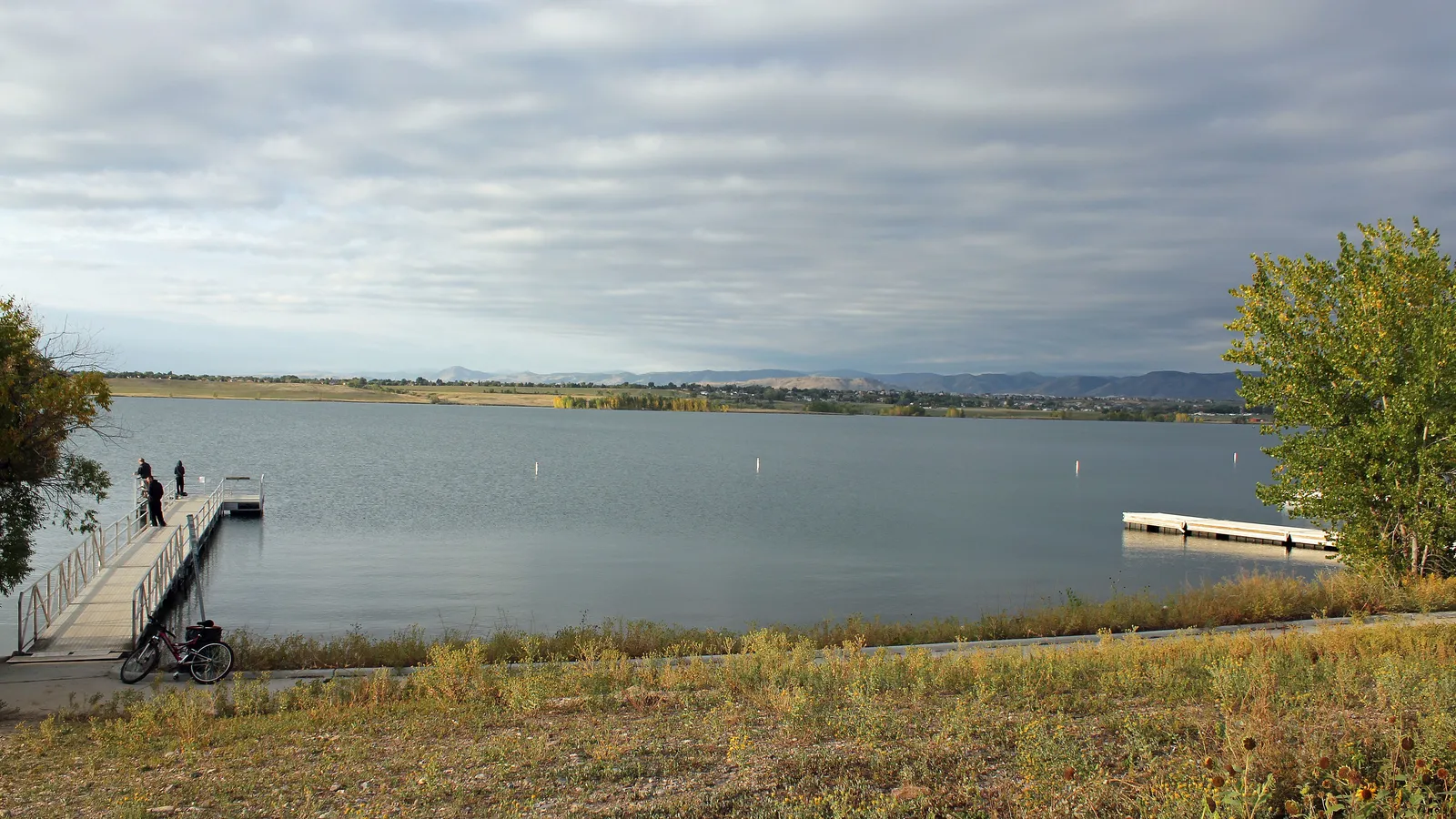 A fishing dock on Standley Lake under a cloudy sky, with a bike parked on the shore