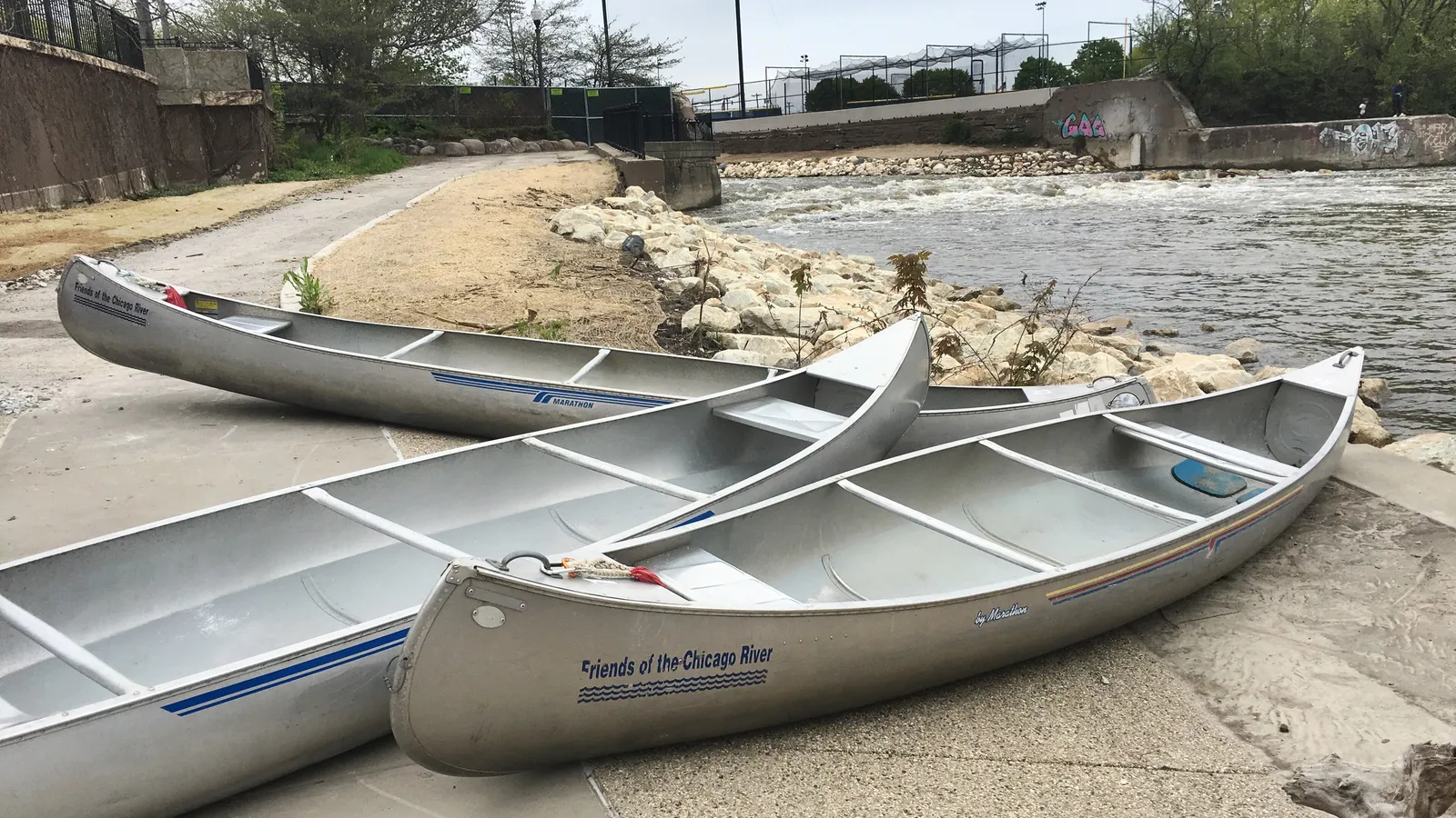 Canoes pulled up on the bank of the North Branch of the Chicago River at River Park