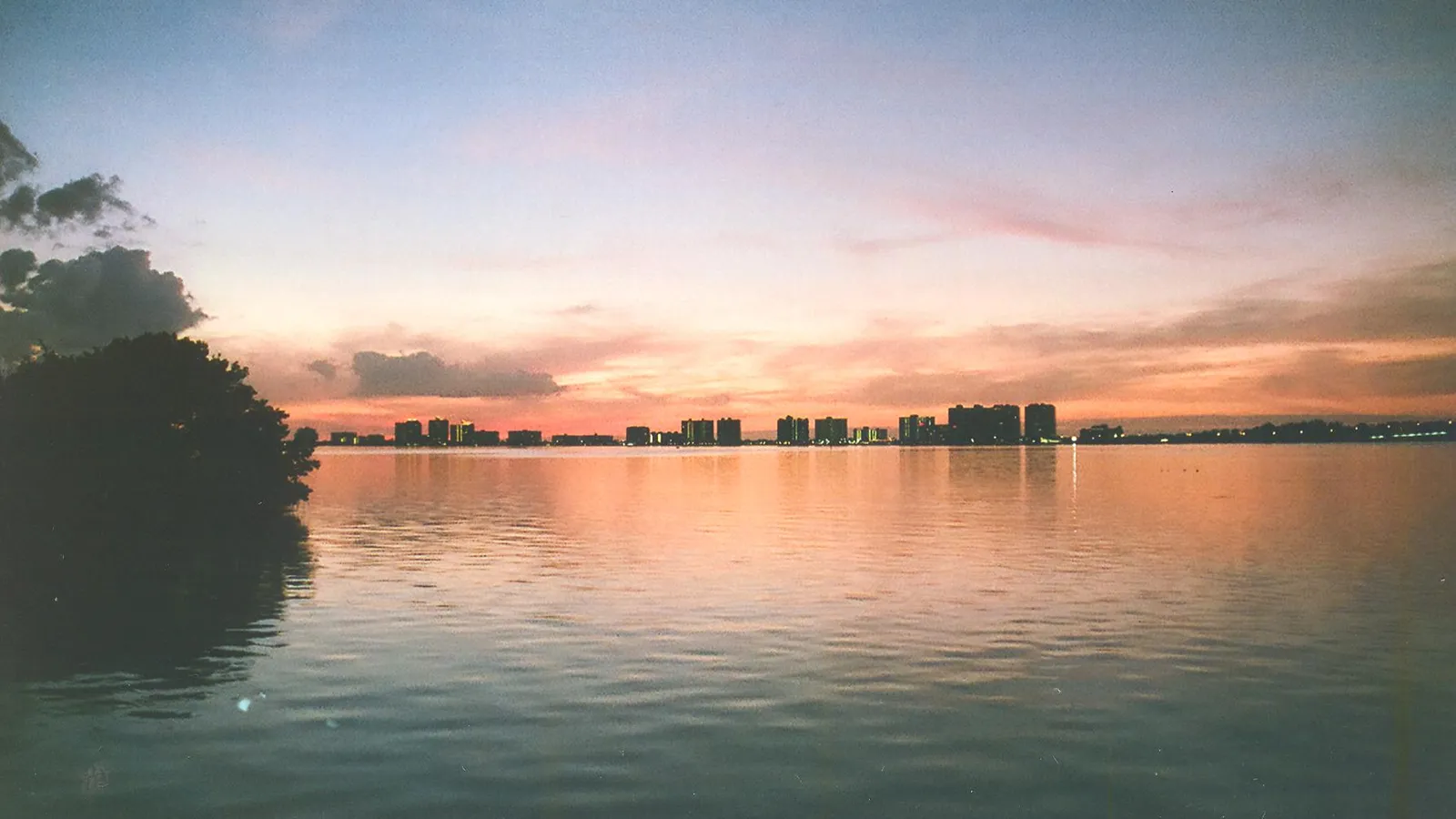 Sunset over calm Clearwater Harbor, with the Sand Key towers on the horizon