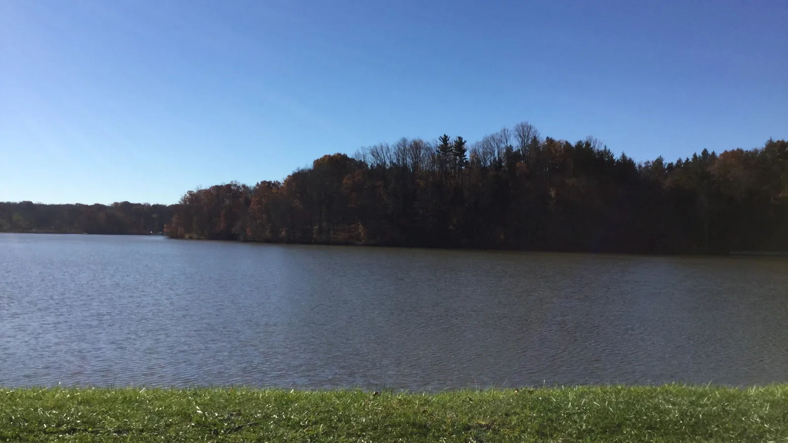 Calm water on Hinckley Lake in the morning, with wooded hills behind