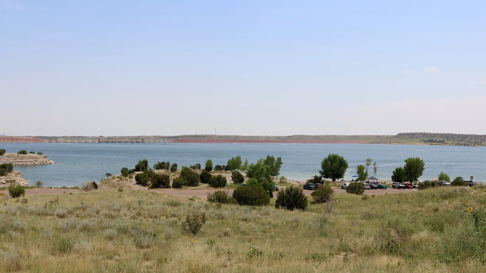 Lake Pueblo seen across grassland and shrubs from Juniper Road