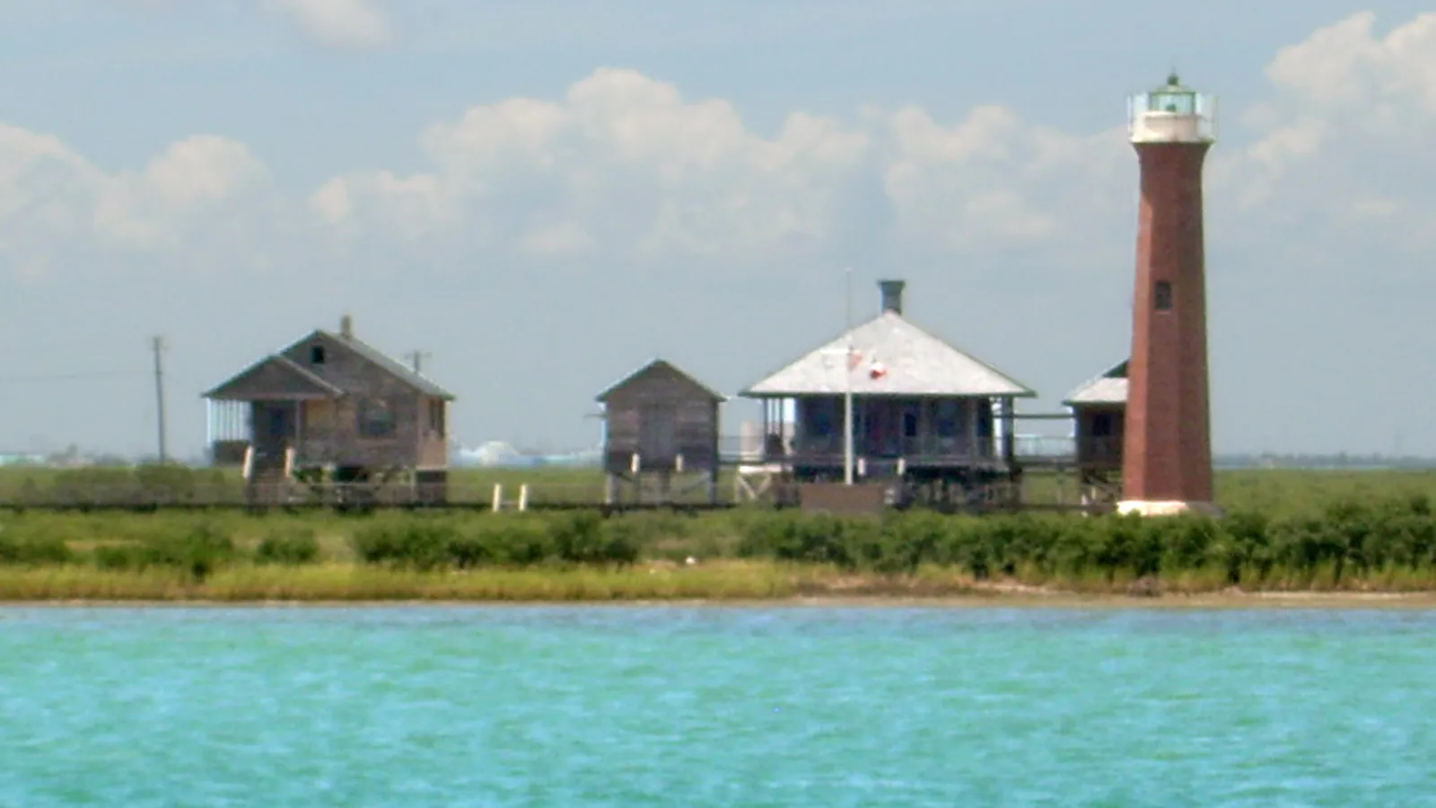 The historic Lydia Ann Lighthouse and cottages across turquoise water near Port Aransas