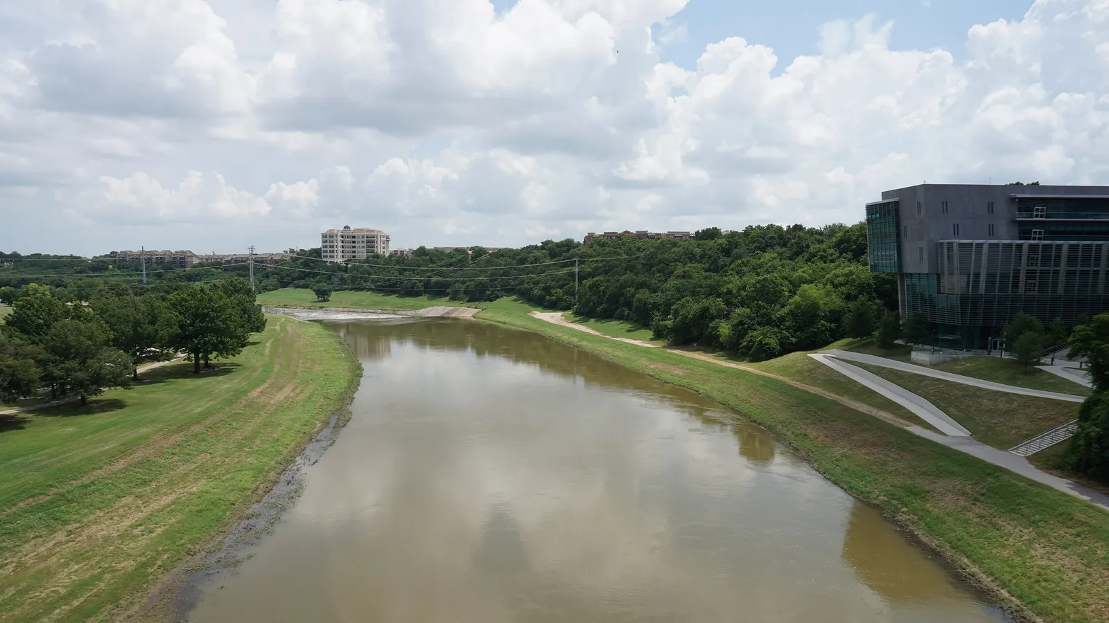 The Trinity River winding between grassy levees and trails in Fort Worth