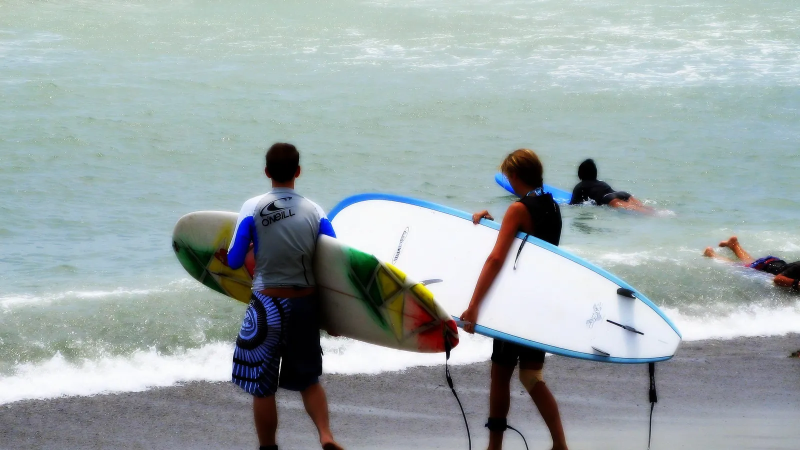 Surfers carrying longboards into the water at Doheny State Beach