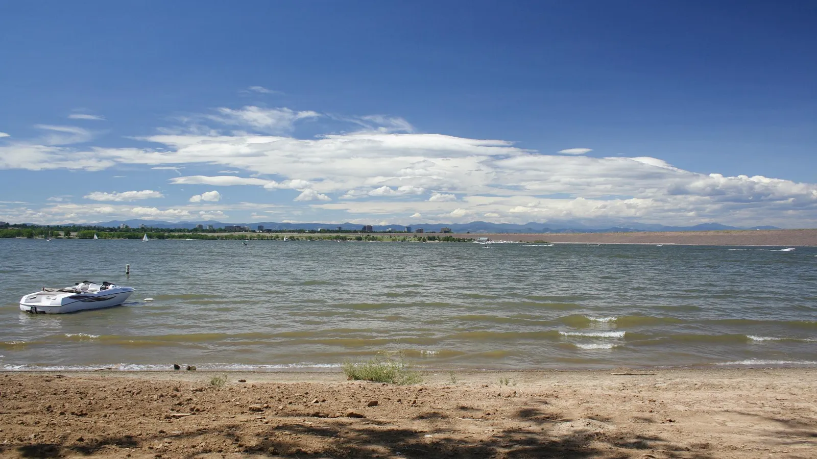 Sandy shore and open water at Cherry Creek Reservoir, with the mountains on the horizon