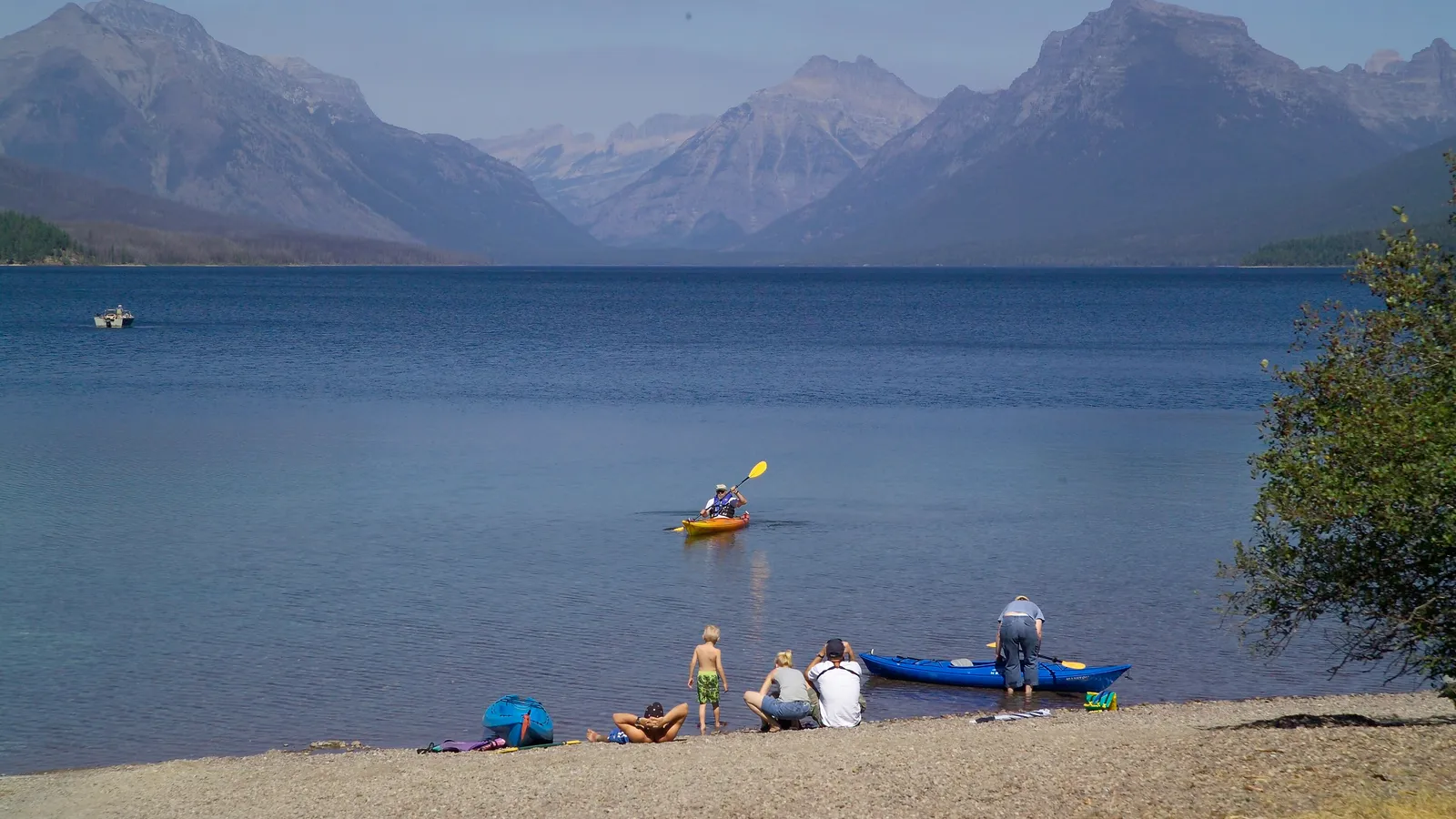 A family launching kayaks from the pebble shore of Lake McDonald