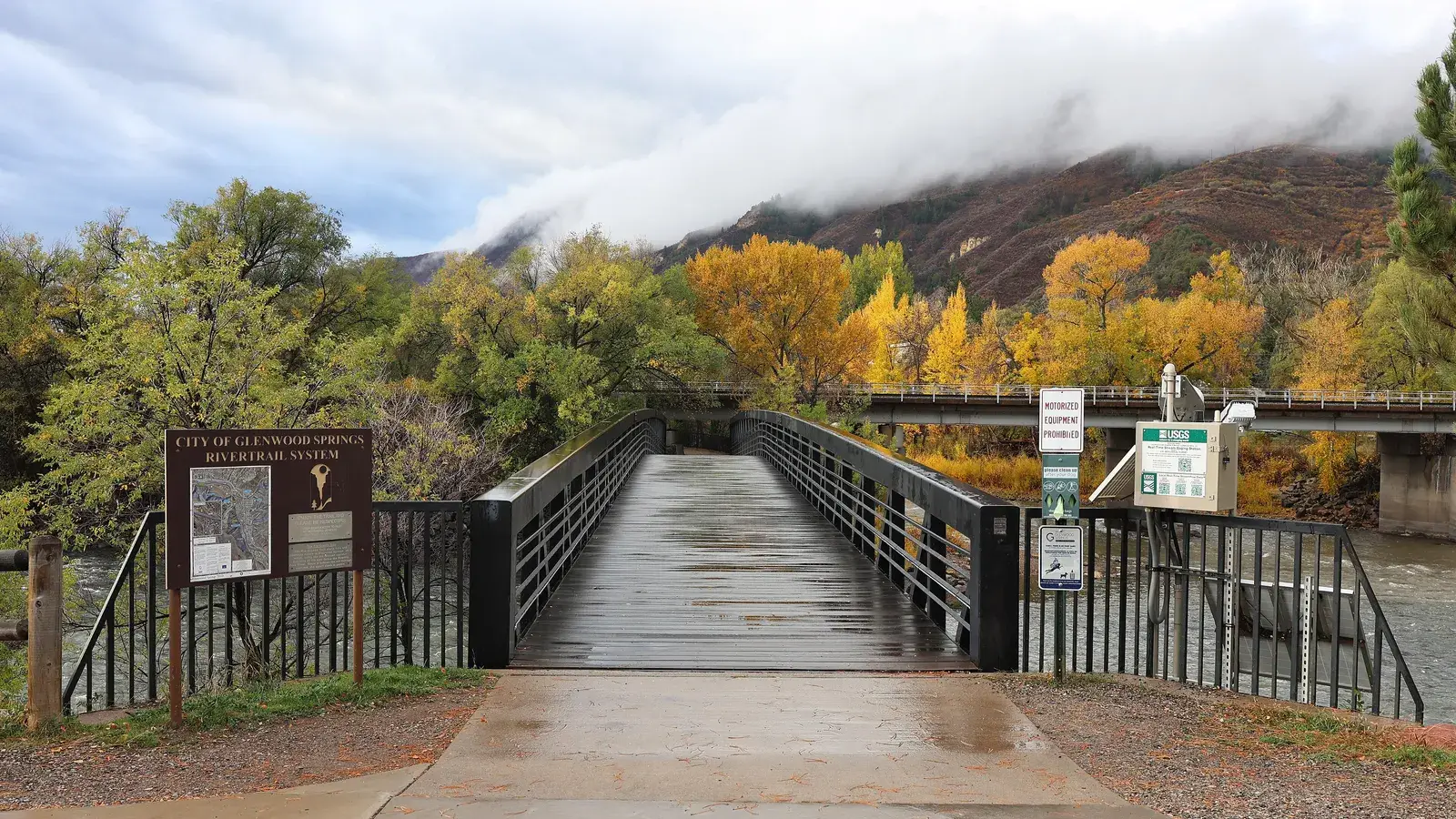 A footbridge over the Colorado River in Glenwood Springs, with fall color on the hillside
