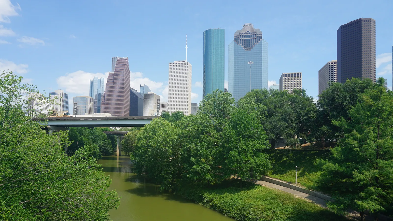 Buffalo Bayou running through the trees of Buffalo Bayou Park below the downtown Houston skyline