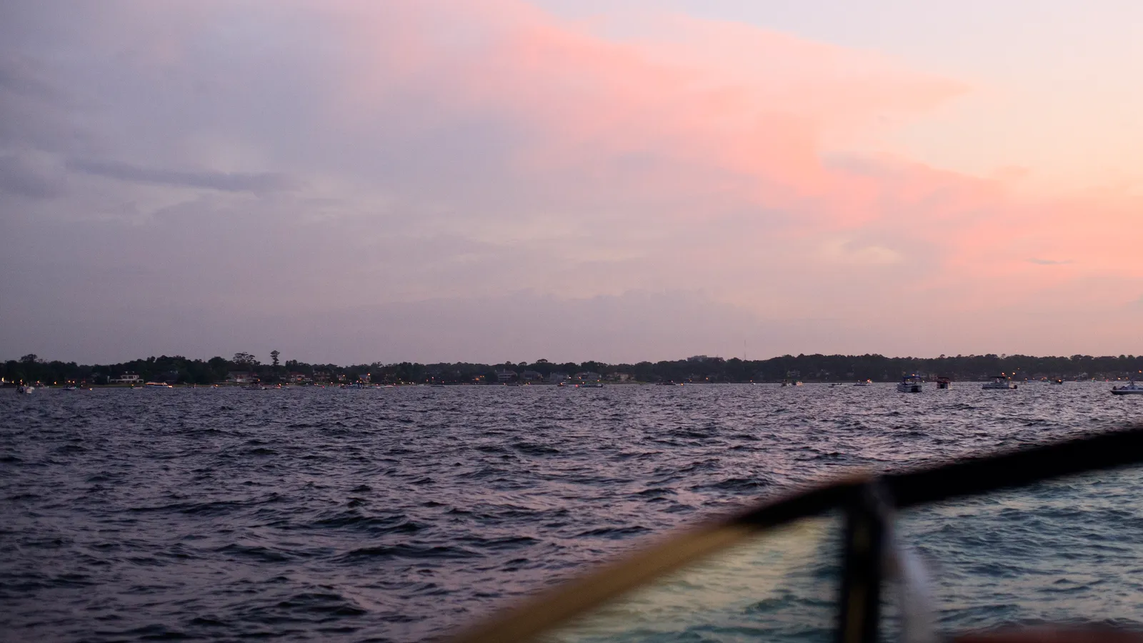 Open water on Lake Conroe at dusk, with boats and a wooded shoreline in the distance