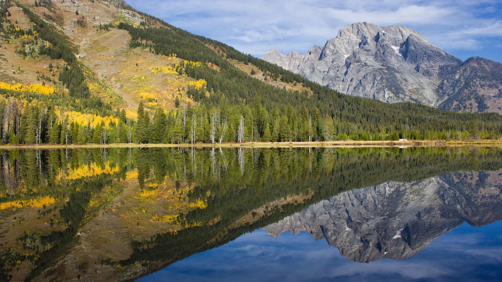 Fall aspens and the Teton peaks reflected in the clear, calm water of String Lake