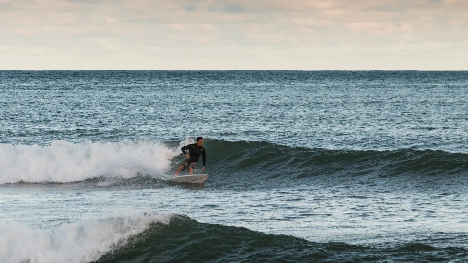 A surfer riding a small wave in Kalapaki Bay