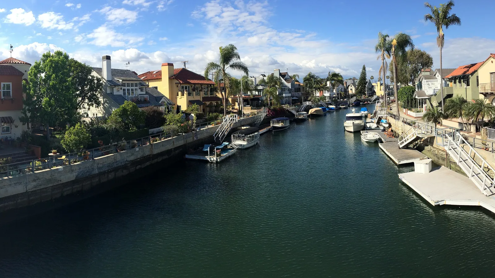 A Naples canal in Long Beach lined with waterfront homes, palms and private docks