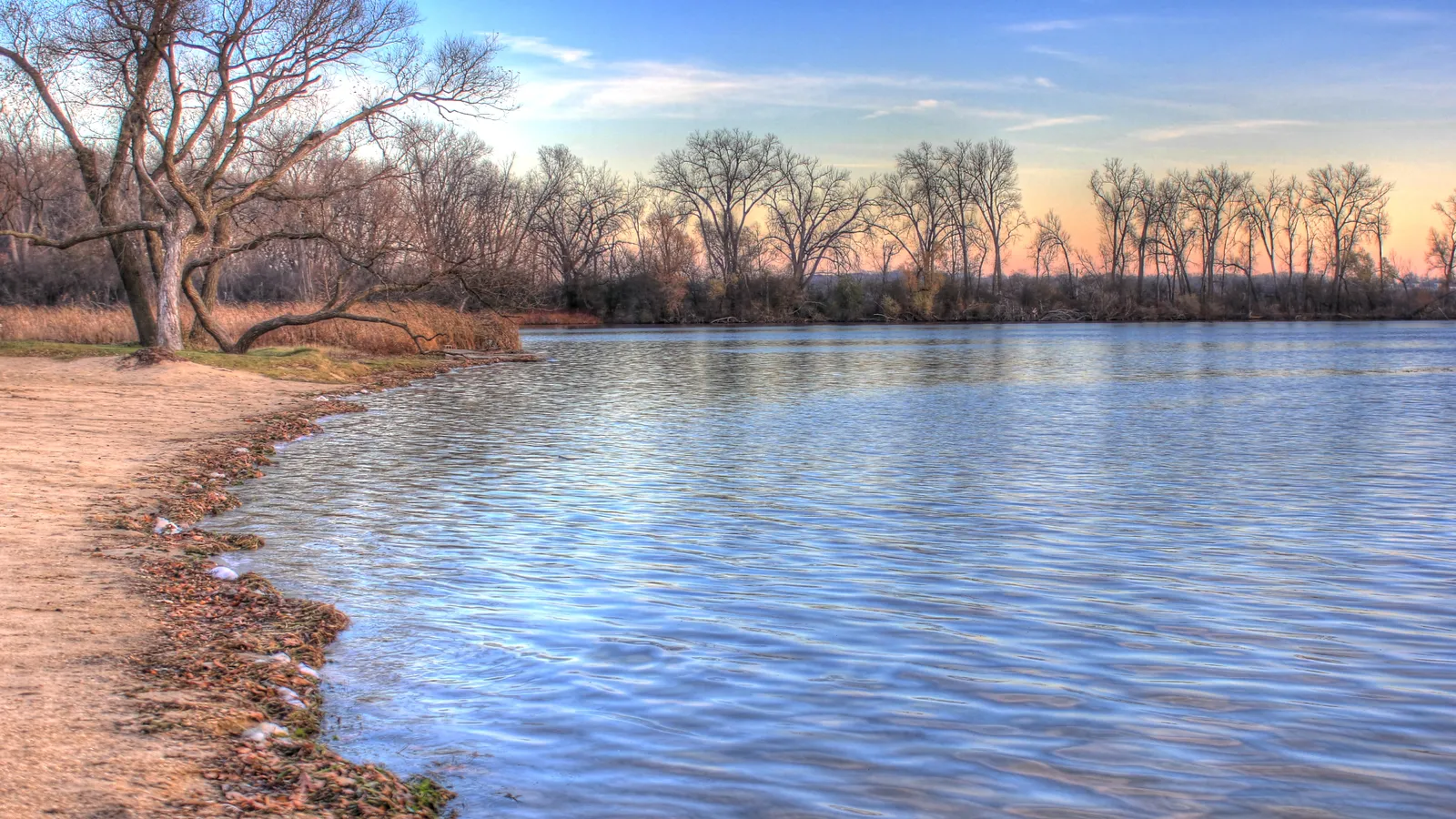 Calm water and a sandy shore on Lake Wingra in late-afternoon light