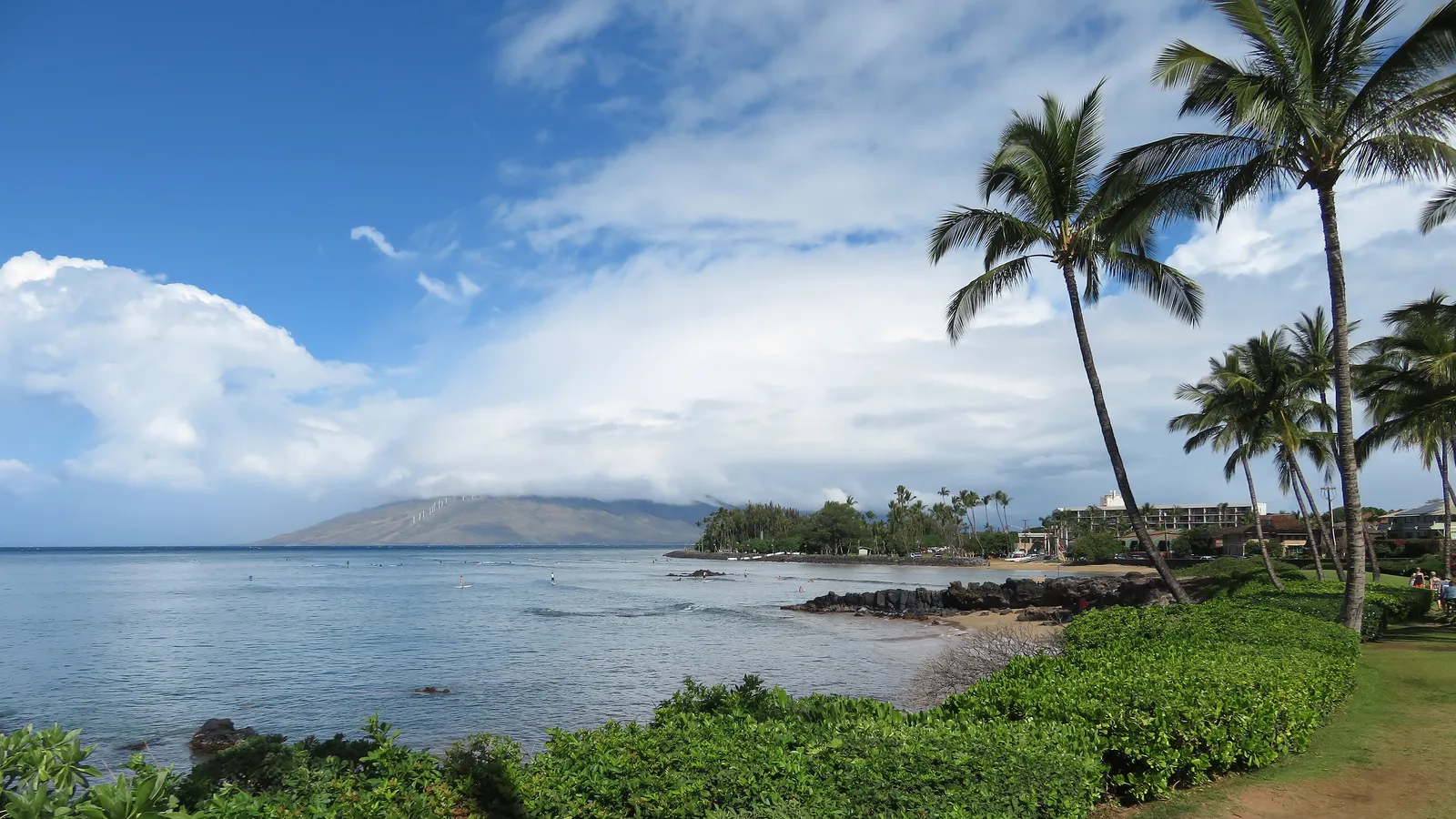 Calm water and lava rocks along the Kihei coast toward Kalama Beach Park, with the West Maui Mountains across the bay