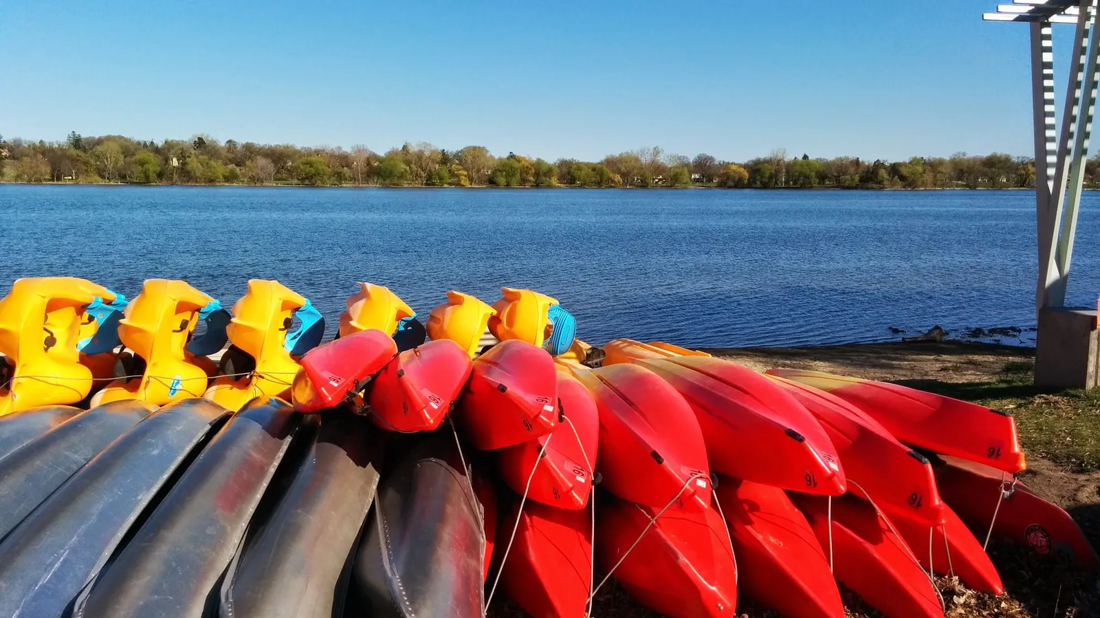Rental canoes and pedal boats lined up on the sand at Lake Nokomis