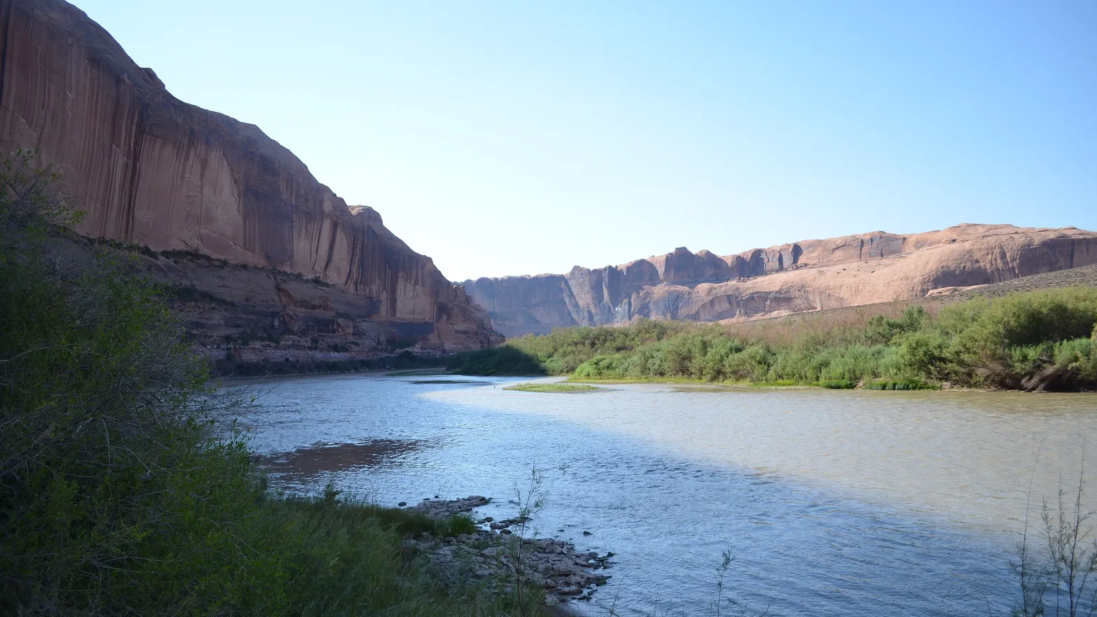 The Colorado River flowing calmly between red rock cliffs near Moab