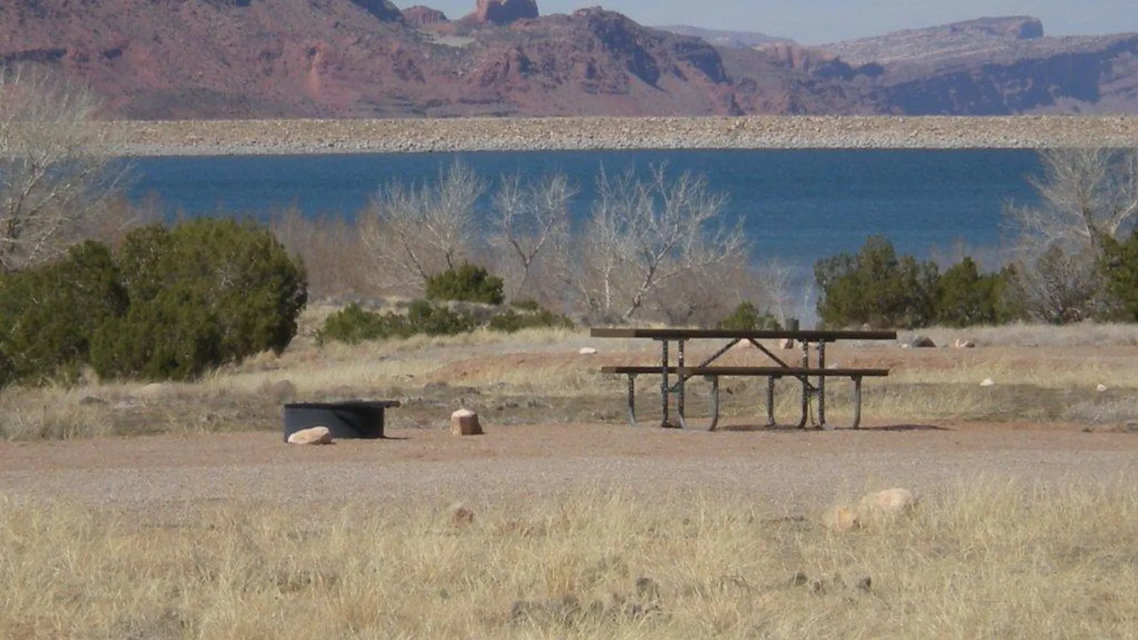 Ken's Lake seen past a picnic table at the BLM campground, with red cliffs beyond