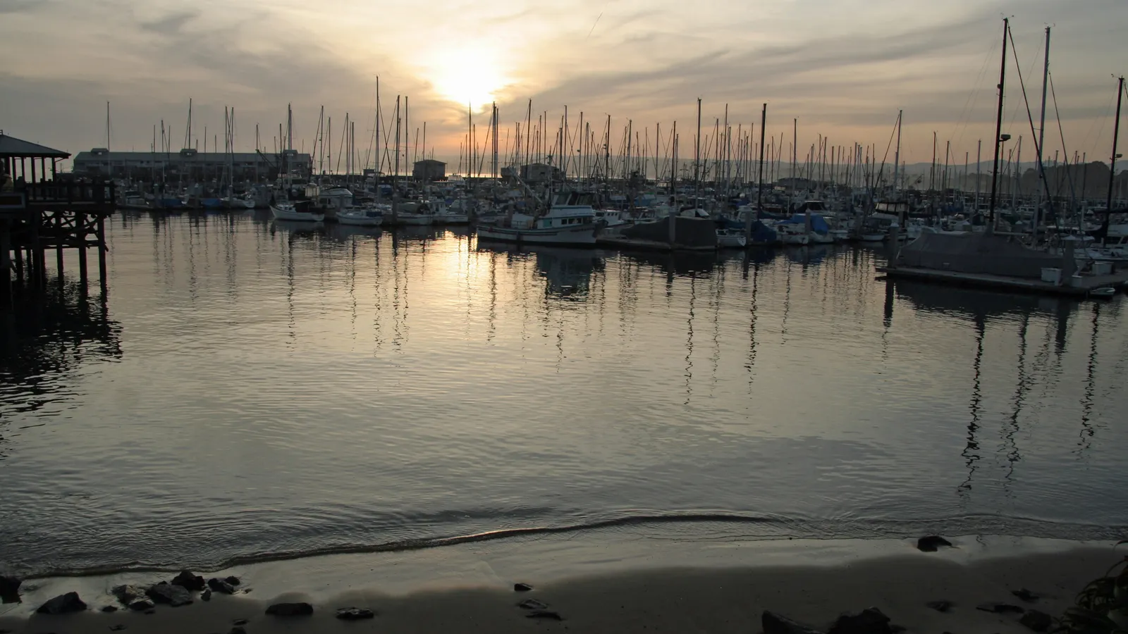 Calm water and moored sailboats in Monterey's marina at sunset