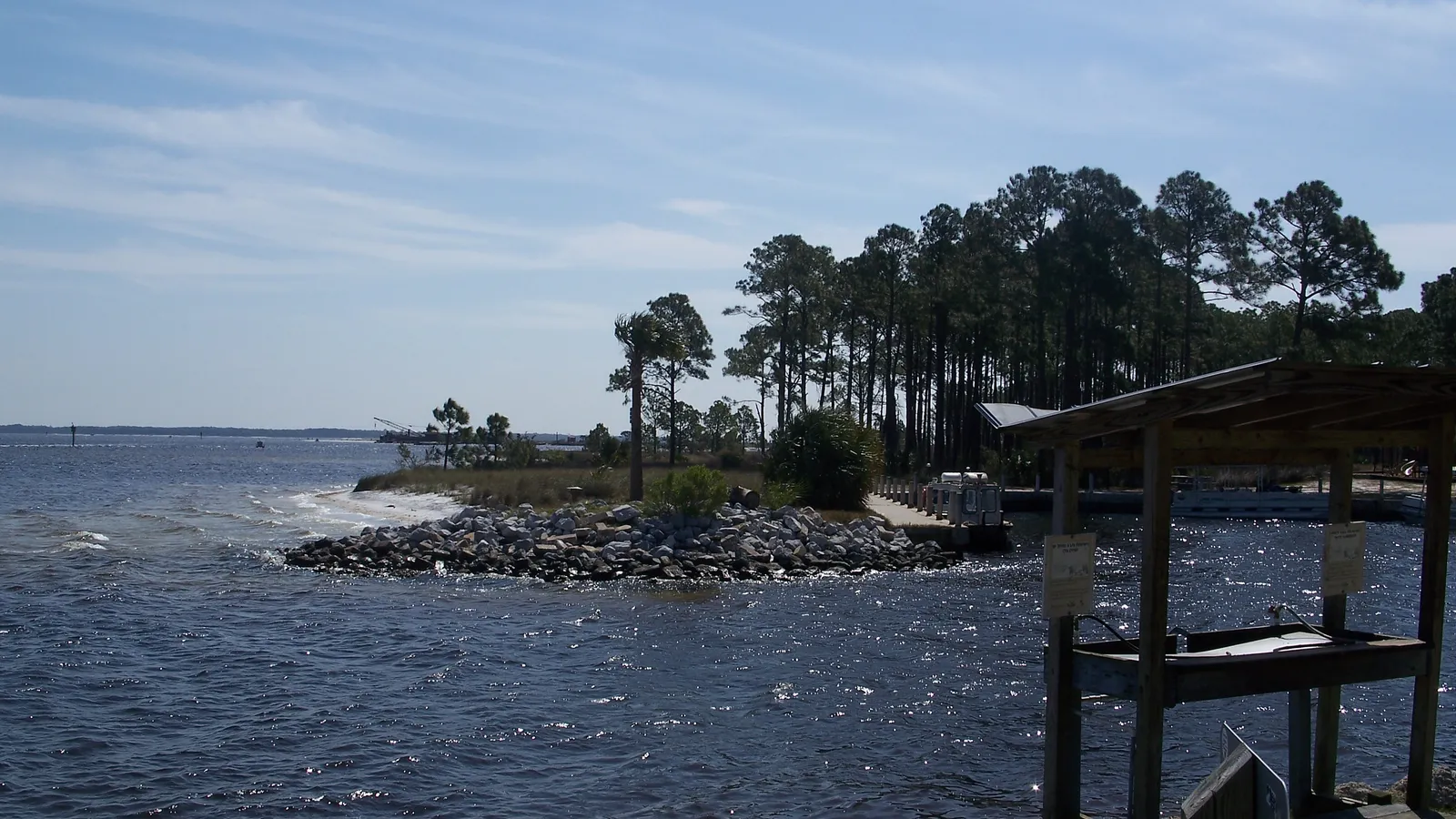 Grand Lagoon seen from the shore of St. Andrews State Park, with pines on a rocky point