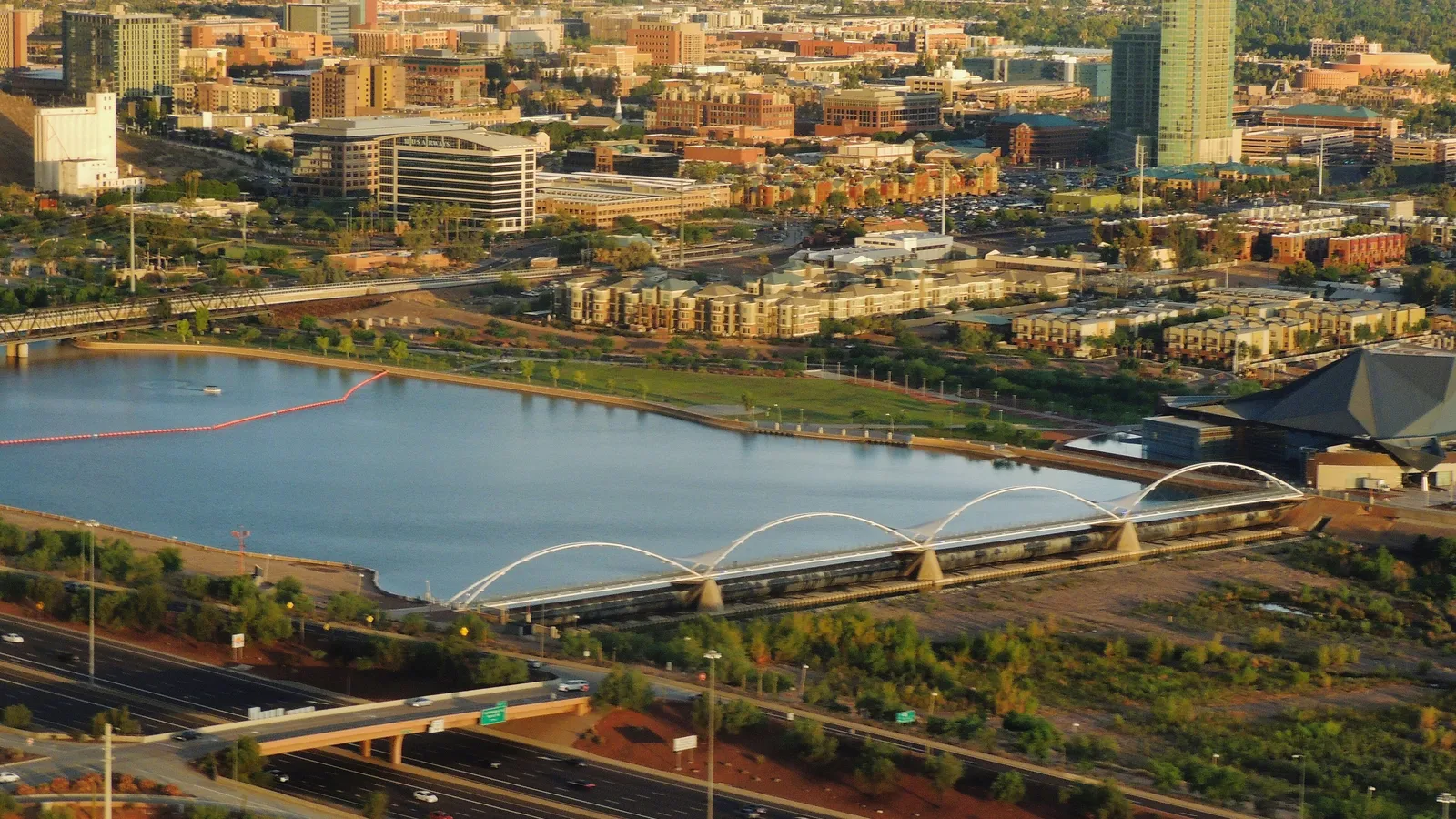 Tempe Town Lake and its arched pedestrian bridge seen from above, with downtown Tempe behind
