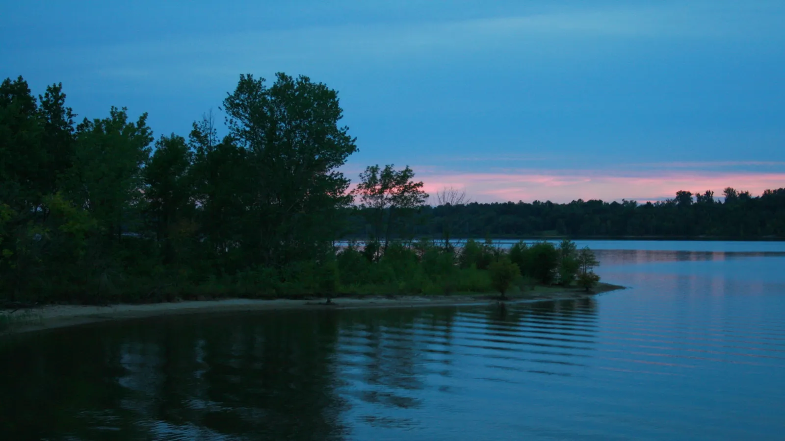 Ripples on Falls Lake at dusk, with a wooded point in the distance