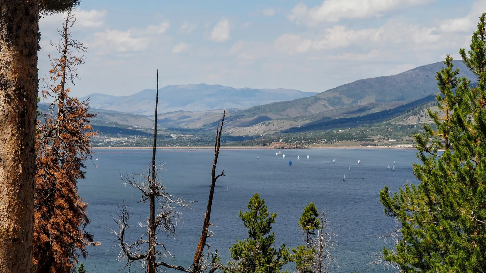 Sailboats out on Dillon Reservoir, with the Dillon Dam and mountains behind
