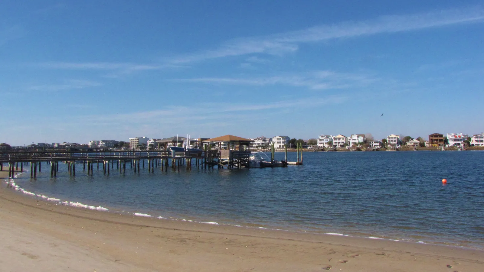A sandy beach and docks along calm Banks Channel in Wrightsville Beach
