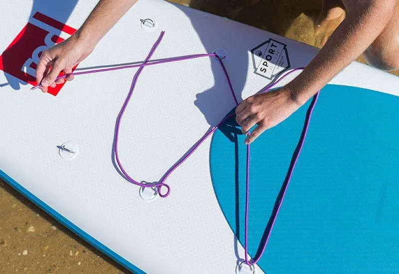 Threading a bungee through the D-rings of a paddle board